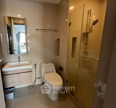 Modern bathroom with sleek fixtures and glass shower enclosure in a contemporary apartment.