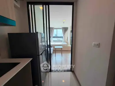 Modern apartment interior with open layout, featuring sleek kitchen and bright living area with large windows.