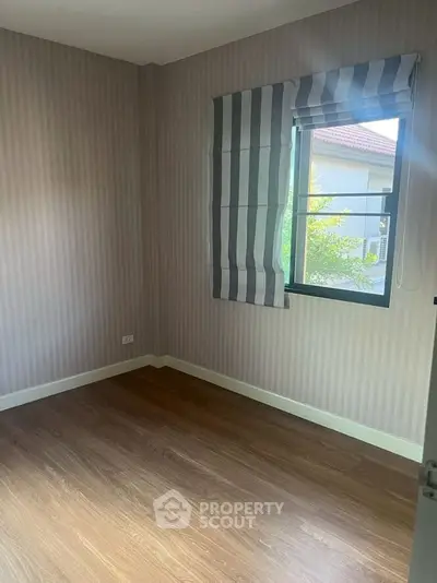 Cozy bedroom with wooden flooring and striped curtains, perfect for a peaceful retreat.
