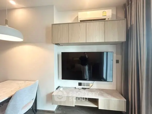 Modern living room with wall-mounted TV and air conditioning unit, featuring sleek furniture and elegant lighting.