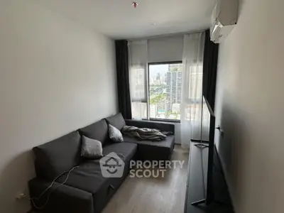 Modern living room with city view, featuring sleek furniture and large window for natural light.