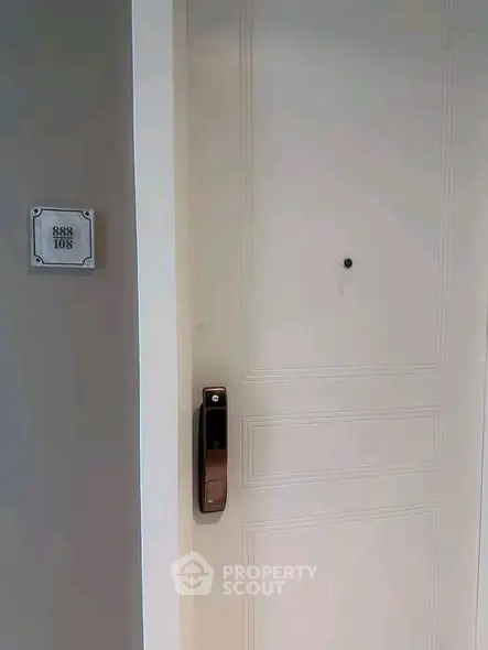Modern apartment door with digital lock and room number, showcasing secure entry.