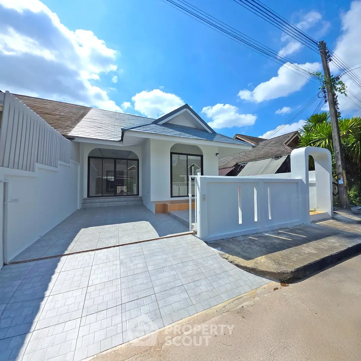 Charming single-story home with modern design and spacious driveway under a clear blue sky.