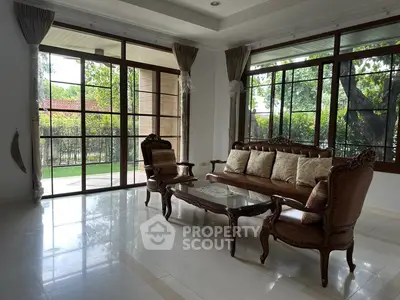Elegant living room with classic furniture and garden view through large windows.