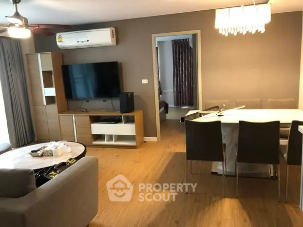 Modern living room with dining area, featuring a sleek TV setup and elegant lighting.