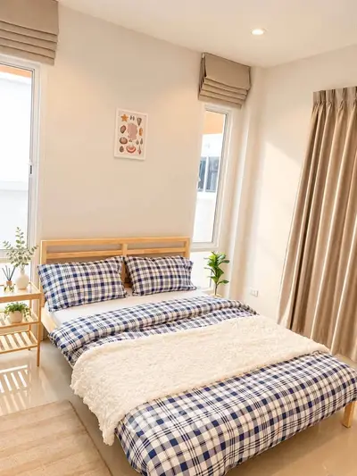 Cozy bedroom with plaid bedding, natural light, and modern decor for a serene living experience.