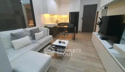 Modern open-plan living room with sleek kitchen, cozy seating, and stylish decor in a contemporary apartment.