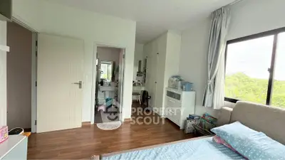 Spacious bedroom with wooden flooring and scenic window view, featuring a cozy bed and ample storage space.