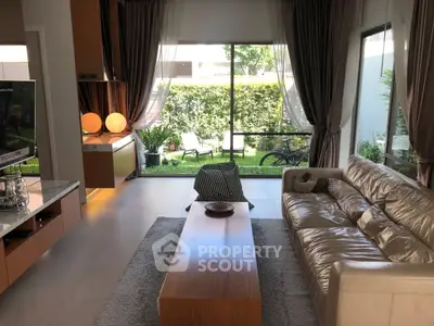 Luxurious living room with modern decor and garden view, featuring elegant curtains and cozy seating.