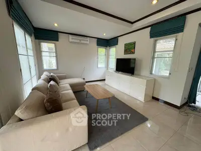 Spacious living room with modern decor, large windows, and comfortable seating in a bright home.