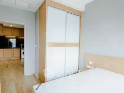 Modern bedroom with sliding wardrobe doors and view into kitchen area.