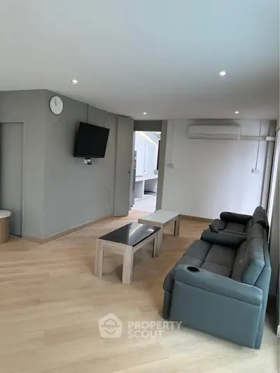 Modern living room with sleek furniture and wall-mounted TV, featuring a cozy ambiance and ample natural light.
