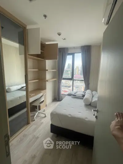 Cozy bedroom with city view, featuring a bed, desk, and ample storage in a modern apartment.