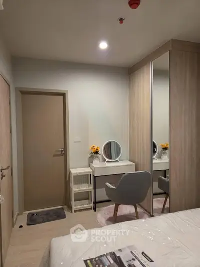 Modern bedroom with stylish vanity and mirrored wardrobe in cozy apartment