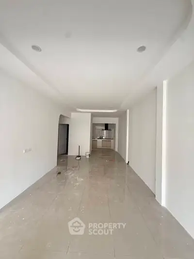 Spacious unfurnished open-plan living area with modern kitchen in a sleek minimalist apartment.