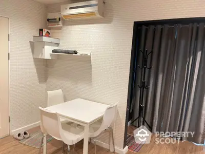 Cozy dining nook with modern white table and chairs, wall-mounted air conditioner, and stylish shelving.