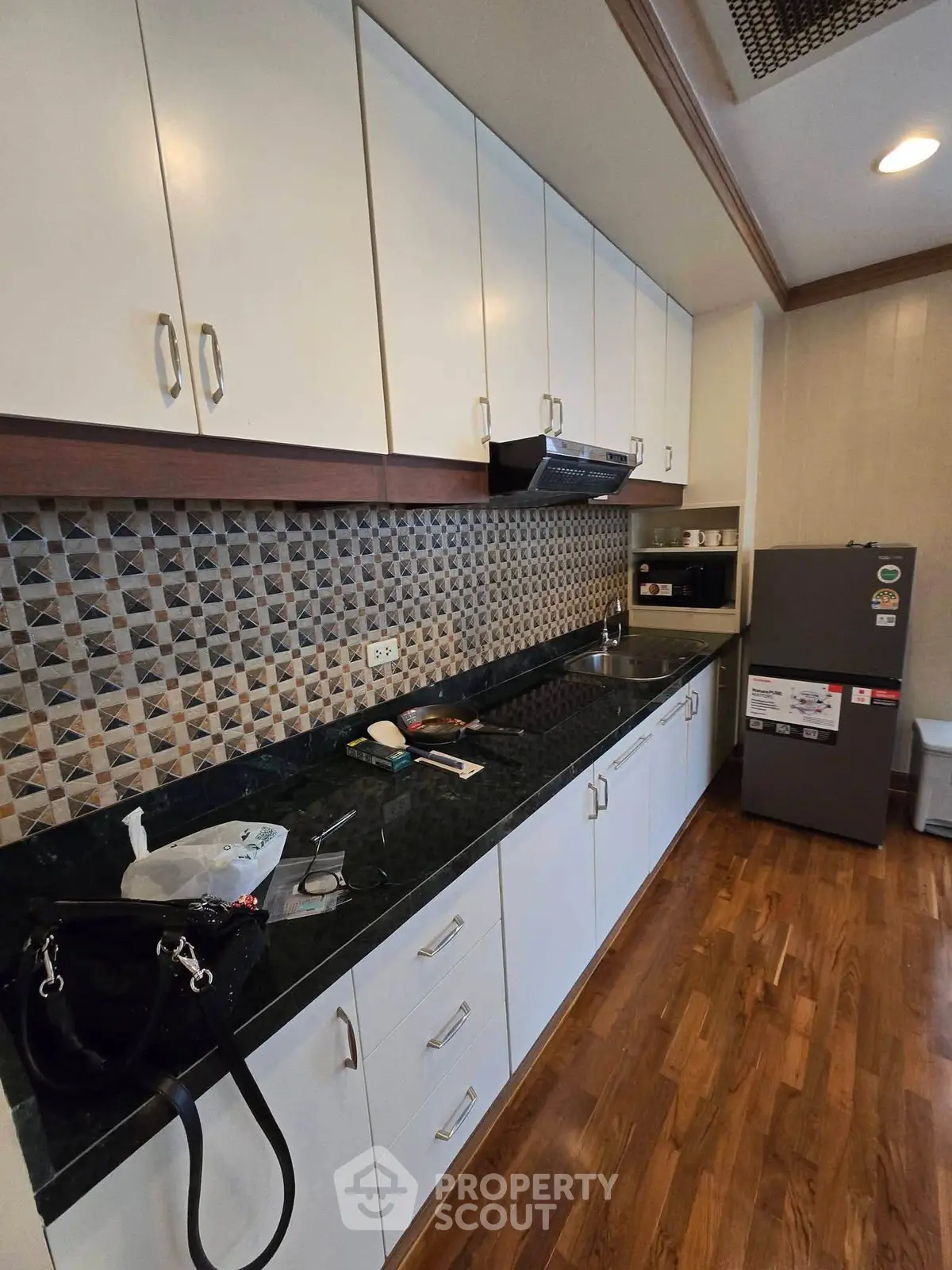Modern kitchen with sleek cabinetry and stylish backsplash in a cozy apartment.