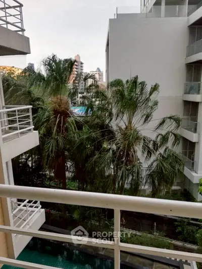 Urban apartment balcony view with lush greenery and modern buildings