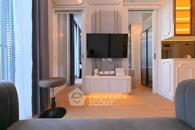 Modern living room with stylish decor and mounted TV, featuring elegant lighting and sleek furniture.