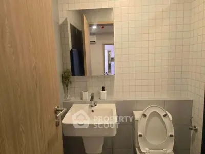 Modern bathroom with sleek sink and toilet, featuring minimalist design and neutral tones.