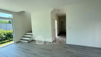 Spacious modern living room with staircase and garden view, perfect for family gatherings.