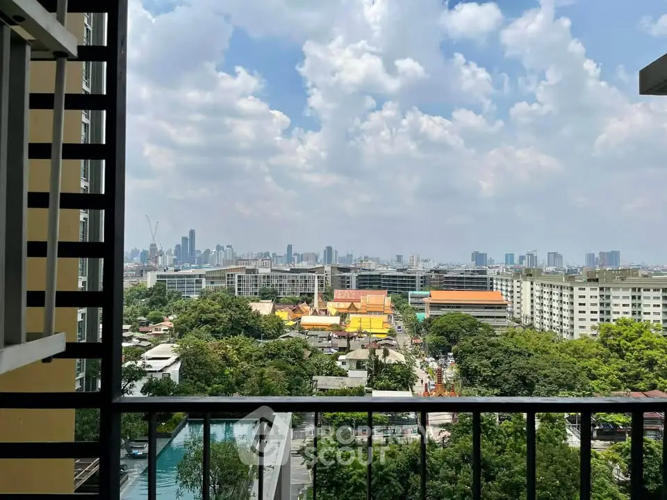 Stunning cityscape view from a high-rise balcony overlooking urban skyline and lush greenery.
