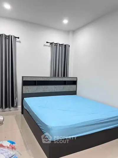 Modern bedroom with sleek bed frame and minimalist design, featuring elegant curtains and neutral tones.