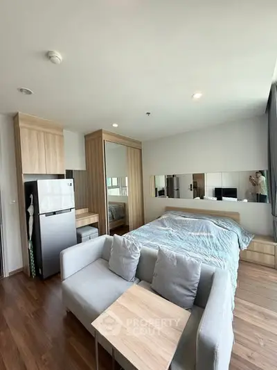 Modern studio apartment with cozy bed, compact kitchen, and stylish decor.