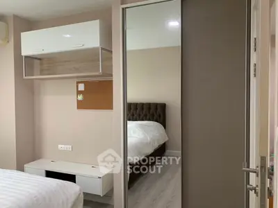 Modern bedroom with sleek storage and mirrored wardrobe in stylish apartment.