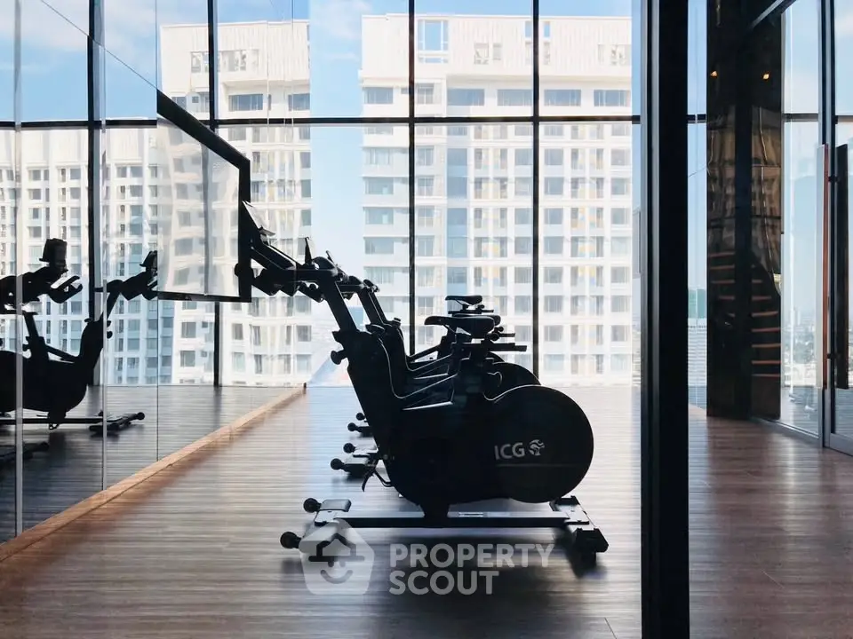 Modern gym with exercise bikes and city view in luxury high-rise building.
