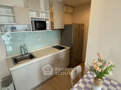 Modern kitchen with sleek cabinetry, microwave, and dining area in stylish apartment.