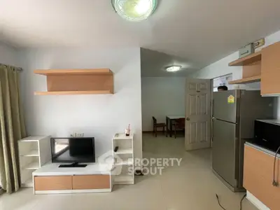 Modern living room with sleek furniture and stainless steel fridge in a cozy apartment.