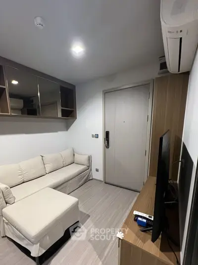 Modern living room with sleek design, featuring a cozy sofa, wall-mounted TV, and stylish storage solutions.