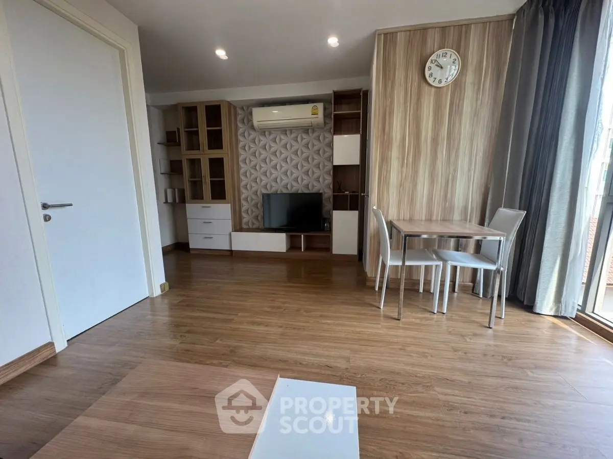 Modern living room with stylish decor and wooden flooring, featuring a TV unit and dining area.