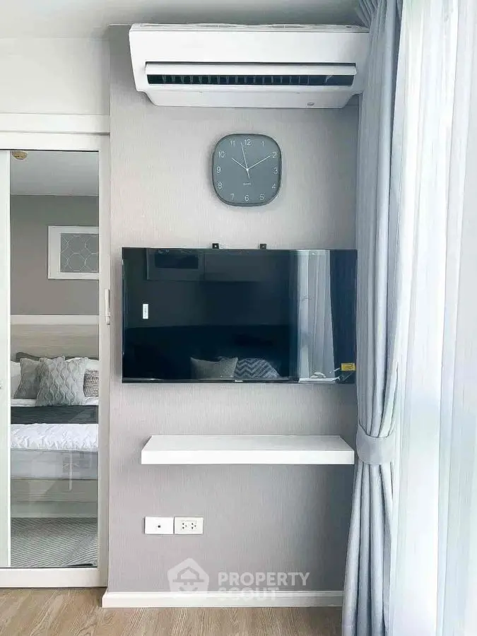 Modern bedroom with wall-mounted TV and air conditioning, featuring sleek design and natural light.