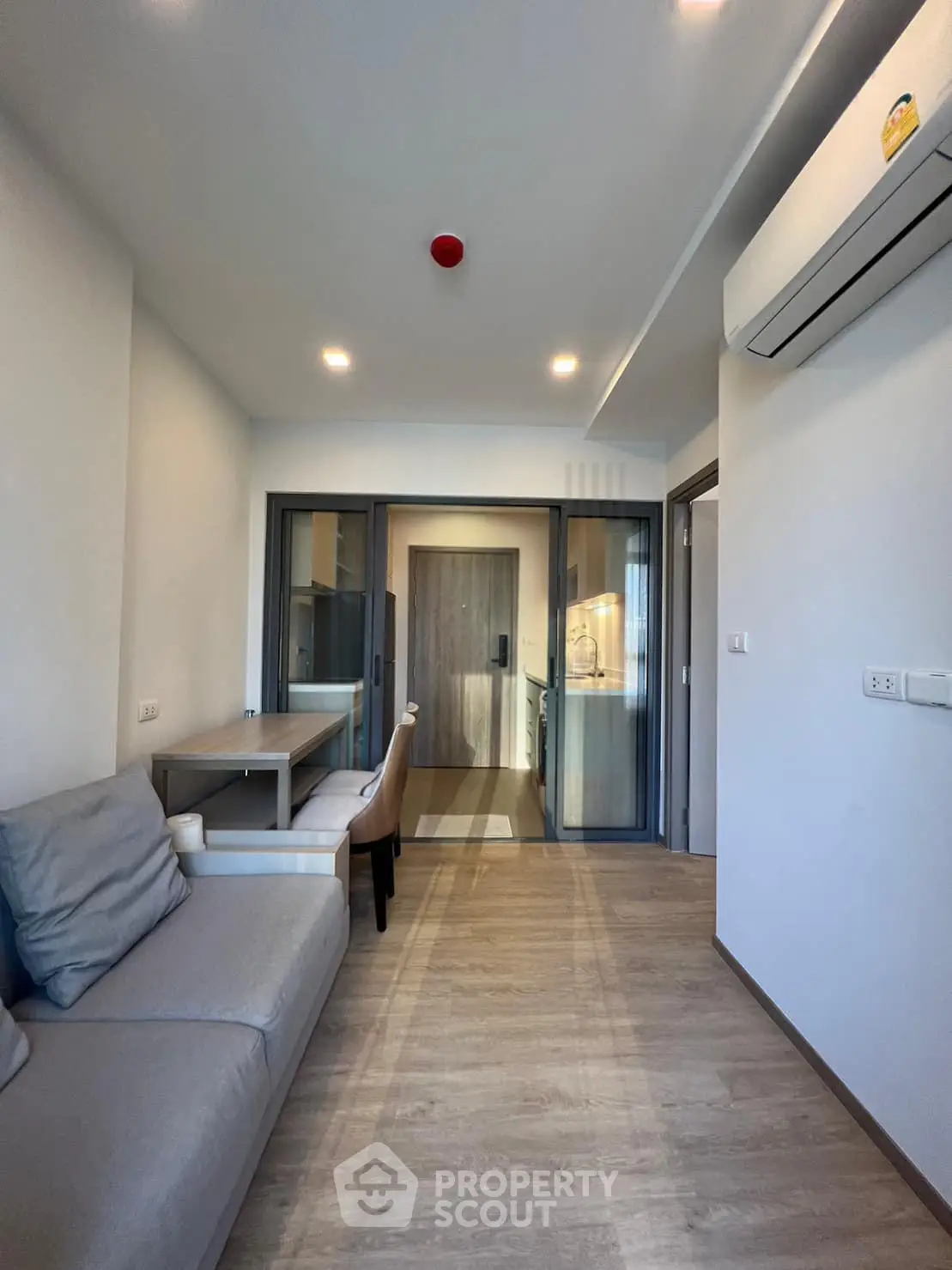 Modern living room with sleek design, featuring a cozy sofa, dining area, and air conditioning unit.