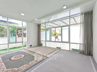 Spacious sunlit room with large windows and elegant carpet, perfect for relaxation or gatherings.