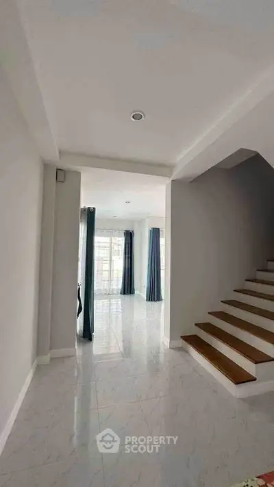 Bright and spacious interior with elegant staircase and large windows in modern home.