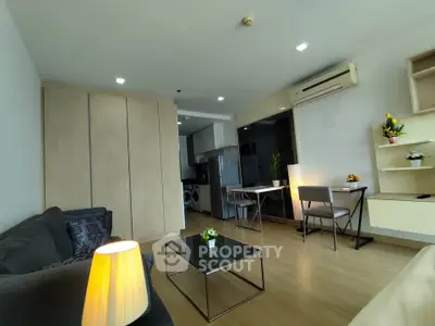 Modern living room with open kitchen, stylish furniture, and wooden flooring in a cozy apartment.