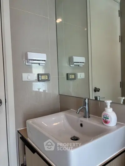 Modern bathroom with sleek sink and mirror, featuring contemporary fixtures and neutral tones.