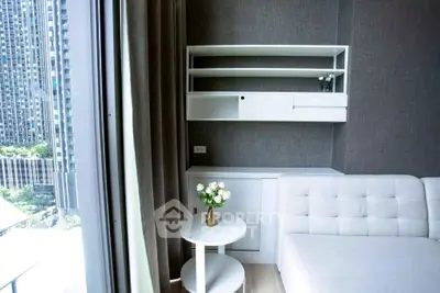 Modern living room with sleek white furniture and large window view in urban apartment.
