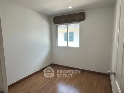 Bright and airy bedroom with polished hardwood floors and a large window inviting ample natural light, perfect for a restful retreat.