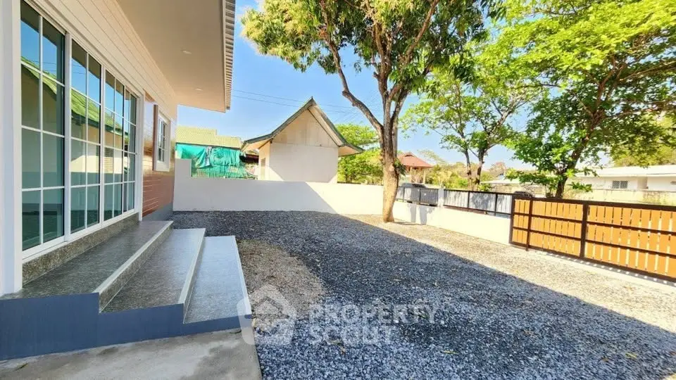 Spacious gravel driveway with modern house and lush greenery