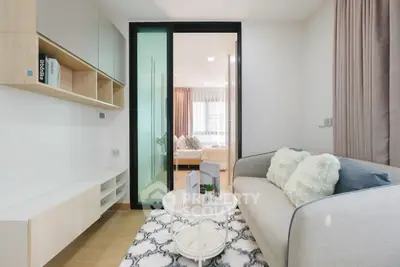 Modern living room with cozy sofa and sliding glass door leading to bedroom.