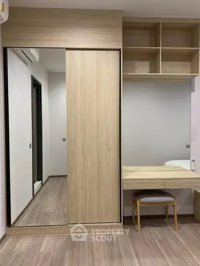 Modern bedroom with built-in wardrobe and study desk, featuring sleek wooden finishes and ample storage space.