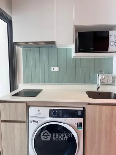 Modern kitchen with washing machine and microwave in compact layout