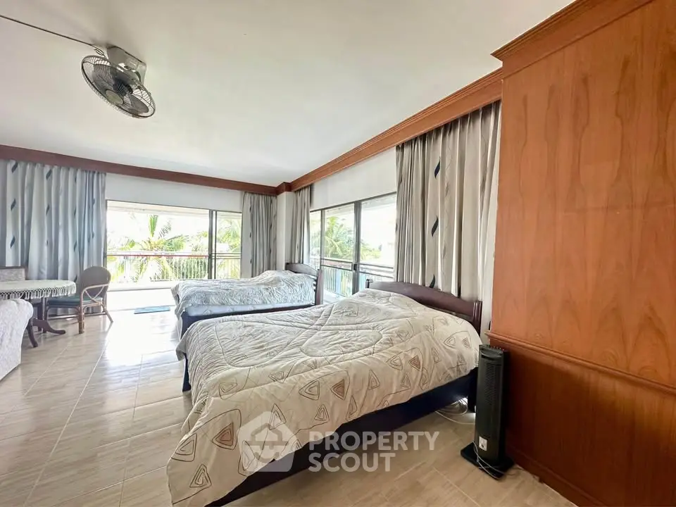 Spacious bedroom with large windows and twin beds, offering a serene view of lush greenery.