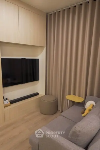 Cozy living room with modern decor, featuring a wall-mounted TV, plush sofa, and elegant curtains.