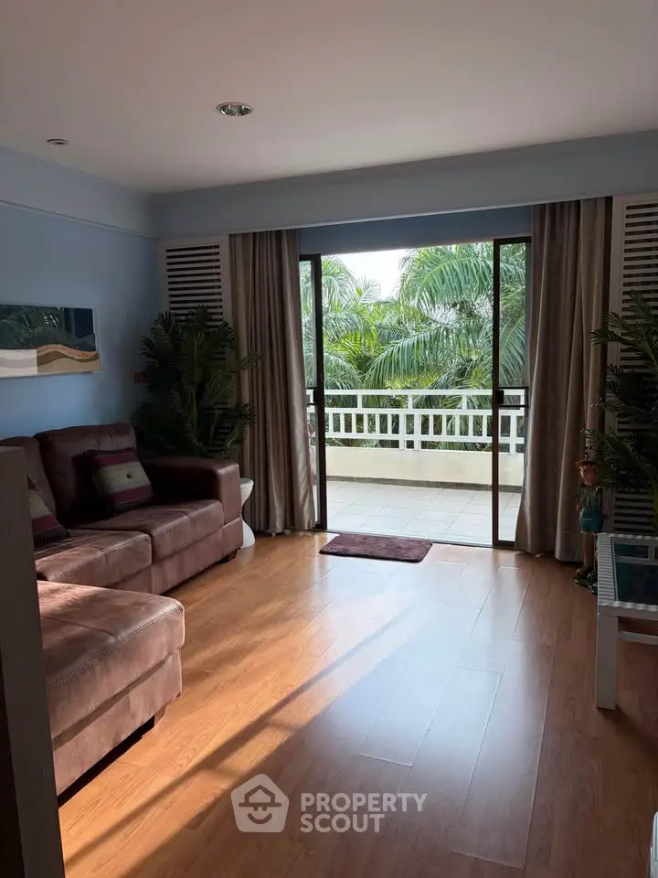 Spacious living room with large balcony and lush garden view, perfect for relaxation and entertaining.