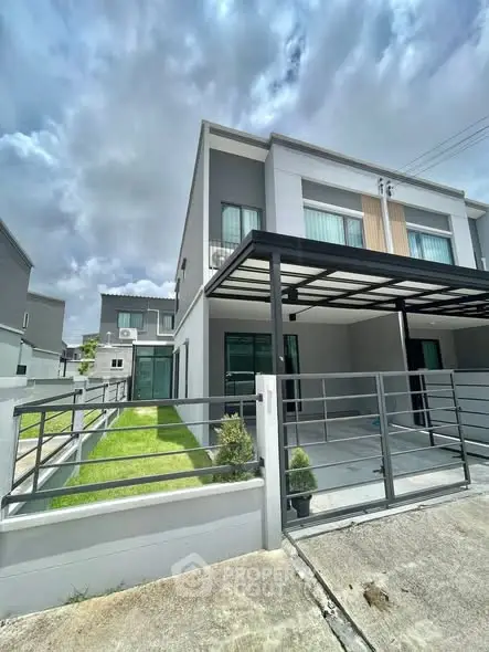 Modern two-story house with sleek design and spacious driveway under cloudy sky.